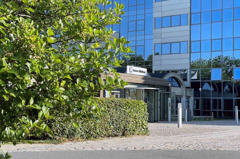 Hovedindgang til Greve Rådhus med buske og træer i forgrunden